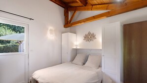 A bedroom with a bed, a window, a wall-mounted light, and a door. - Apartment 'La Clésinerie' with Private Pool, Private Terrace and Wi-Fi (Badefols-sur-Dordogne)