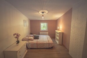 Ein Schlafzimmer mit Bett, Schminktisch, Nachttisch und einem Fenster.