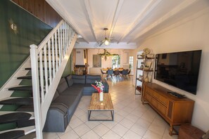 Ein Wohnzimmer mit Treppe, einem Sofa, einem Couchtisch und einem Fernseher.