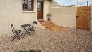 A house with a gravel patio, a wooden gate, and a small table with chairs.