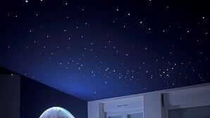 A bedroom with a large illuminated moon mural, a window with blinds, and a radiator.