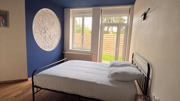 Un dormitorio con una cama, un adorno circular en la pared y una ventana con vistas a la vegetación.