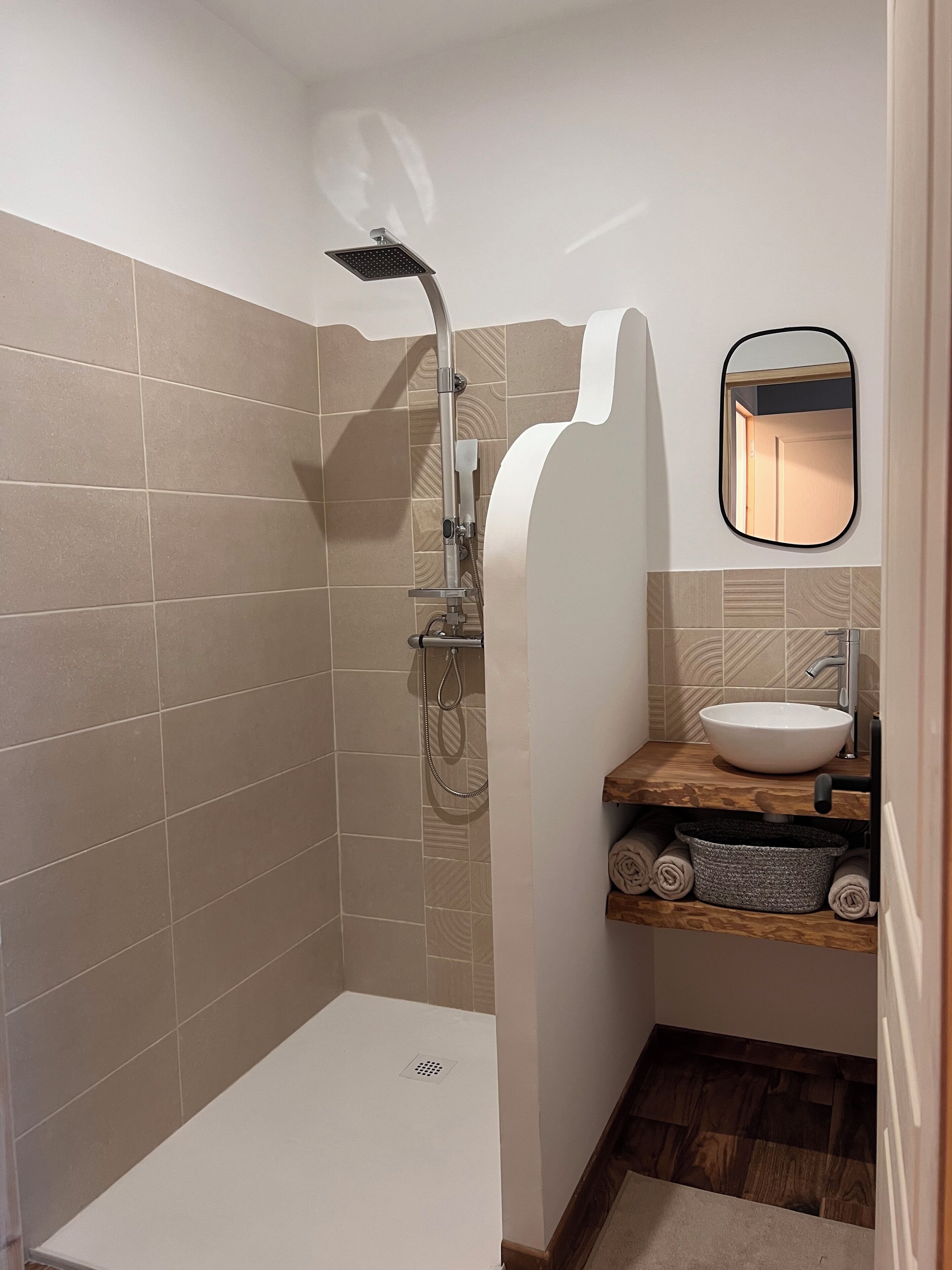 A modern bathroom with a shower, a sink, and a mirror.