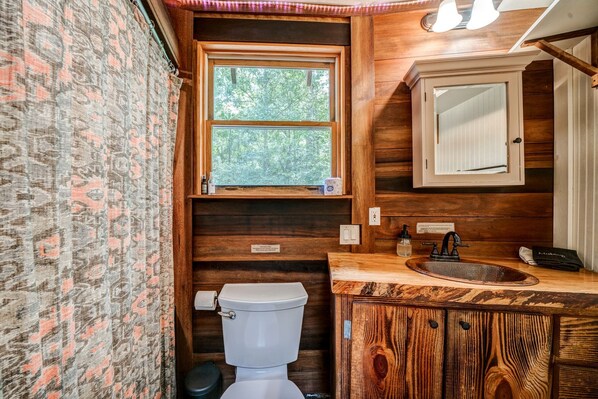 A bathroom with a wooden vanity, a window, and a toilet.
