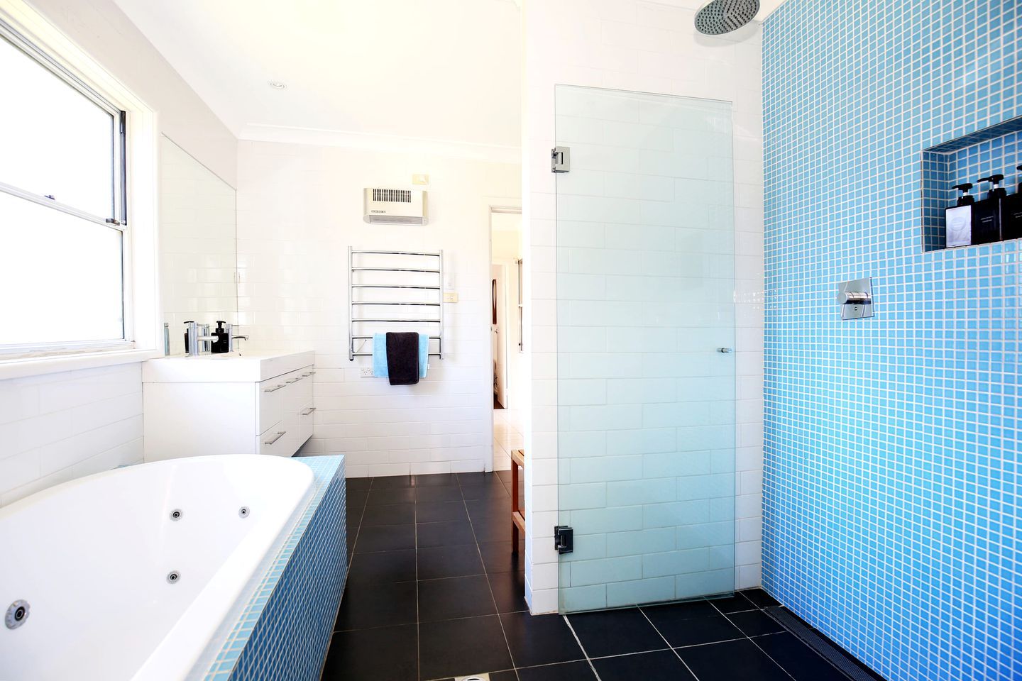 A modern bathroom with a bathtub, a shower area, and a tiled wall.