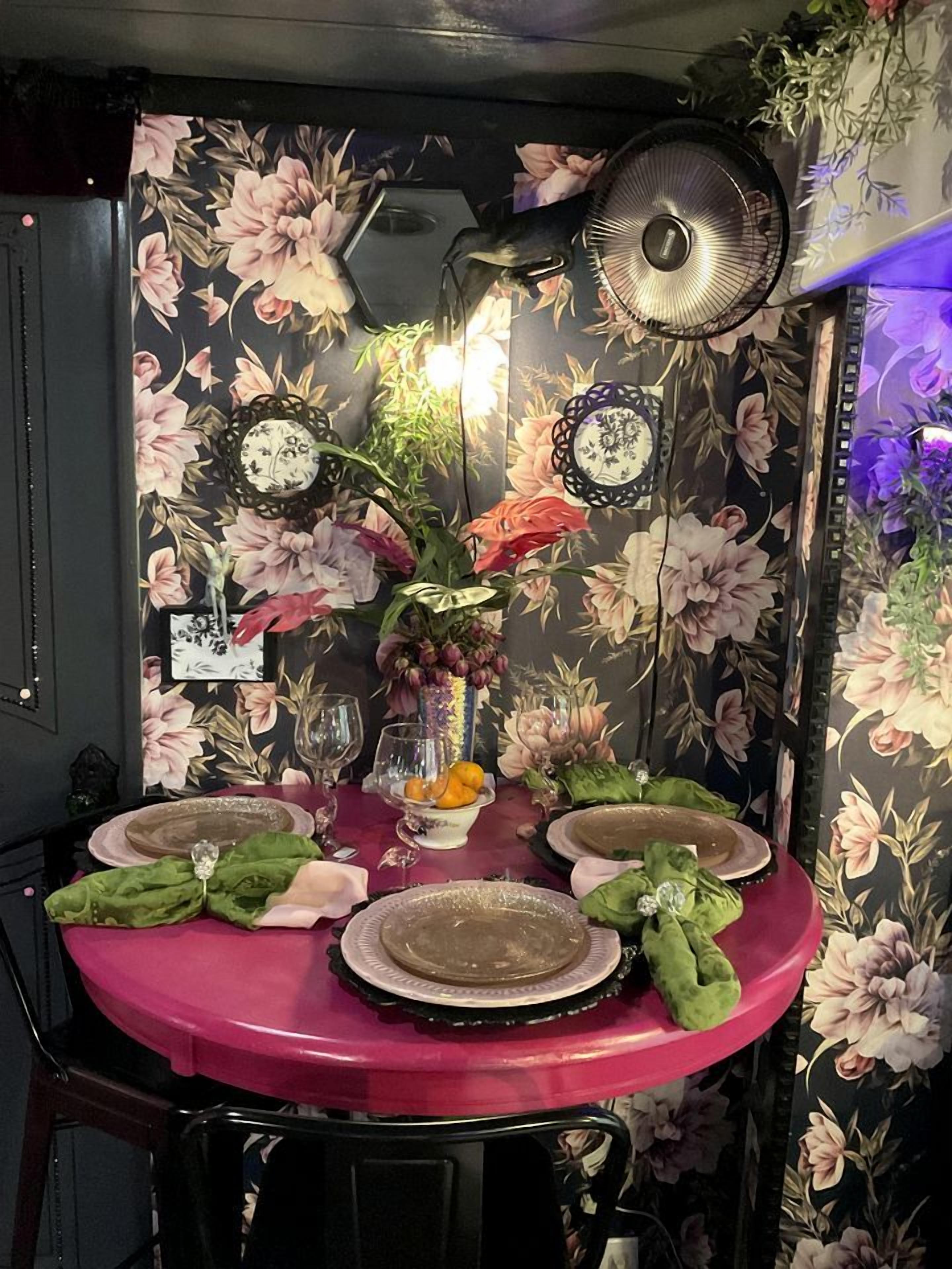 Une table à manger dressée avec des assiettes, un vase rempli de fleurs et un éventail.