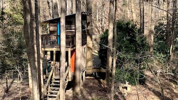 A treehouse with a wooden staircase leading up to it, surrounded by trees.