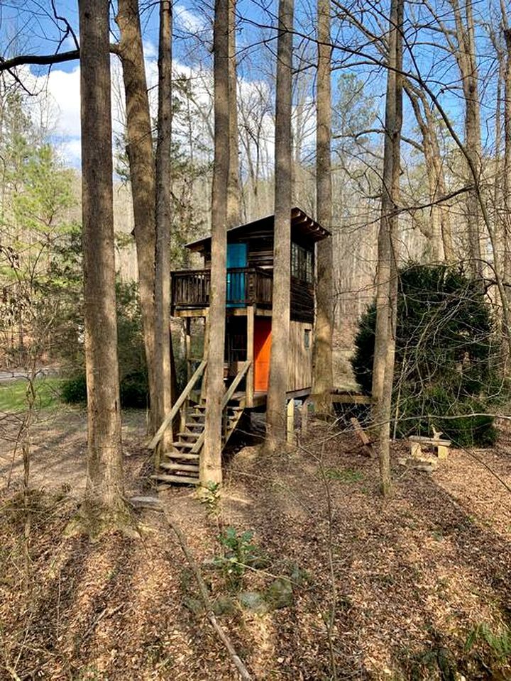 Una casetta sugli alberi con una scala di legno che conduce a una piattaforma con ringhiera.