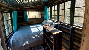 A cabin with a bed, a desk, and large windows. - Rustic Woodland Treehouse with Fire Pit in Talking Rock, Georgia (Pickens County)