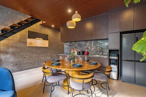 Una cocina moderna con refrigerador empotrado, una mesa de comedor preparada para seis comensales y una escalera que sube a un nivel superior.