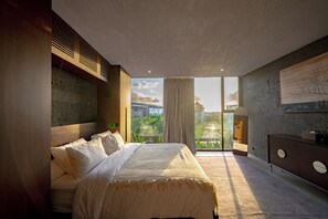 Un dormitorio moderno con una cama grande, vistas a la vegetación, un balcón y un aparador moderno.