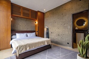 Un dormitorio moderno con una cama grande, paneles de madera, una pared de acento de concreto, un espejo y una planta en maceta.
