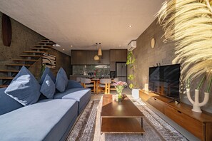 Una sala de estar moderna con sofá, mesa de centro y televisor.