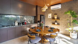 Une cuisine moderne avec une table de salle à manger ronde, des placards intégrés et une grande fenêtre donnant sur un jardin.