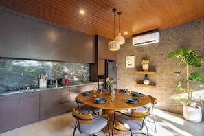Una cocina moderna con una mesa redonda, armarios empotrados y un amplio ventanal con vistas a un jardín.