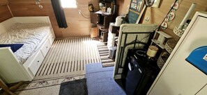 A compact room with a bed, a small desk, and a kitchenette area.