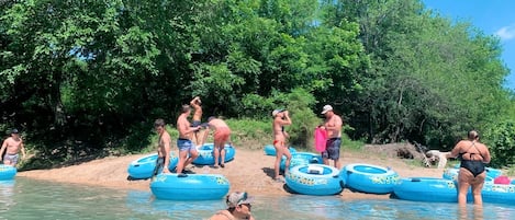 A group of people on inflatable rafts in a body of water with trees in the background.