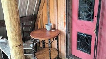 A wooden staircase leading to a room with a pink door and a small table with a cup.