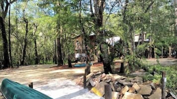 Un camping con una canoa verde, una mesa de picnic y una cabaña al fondo.