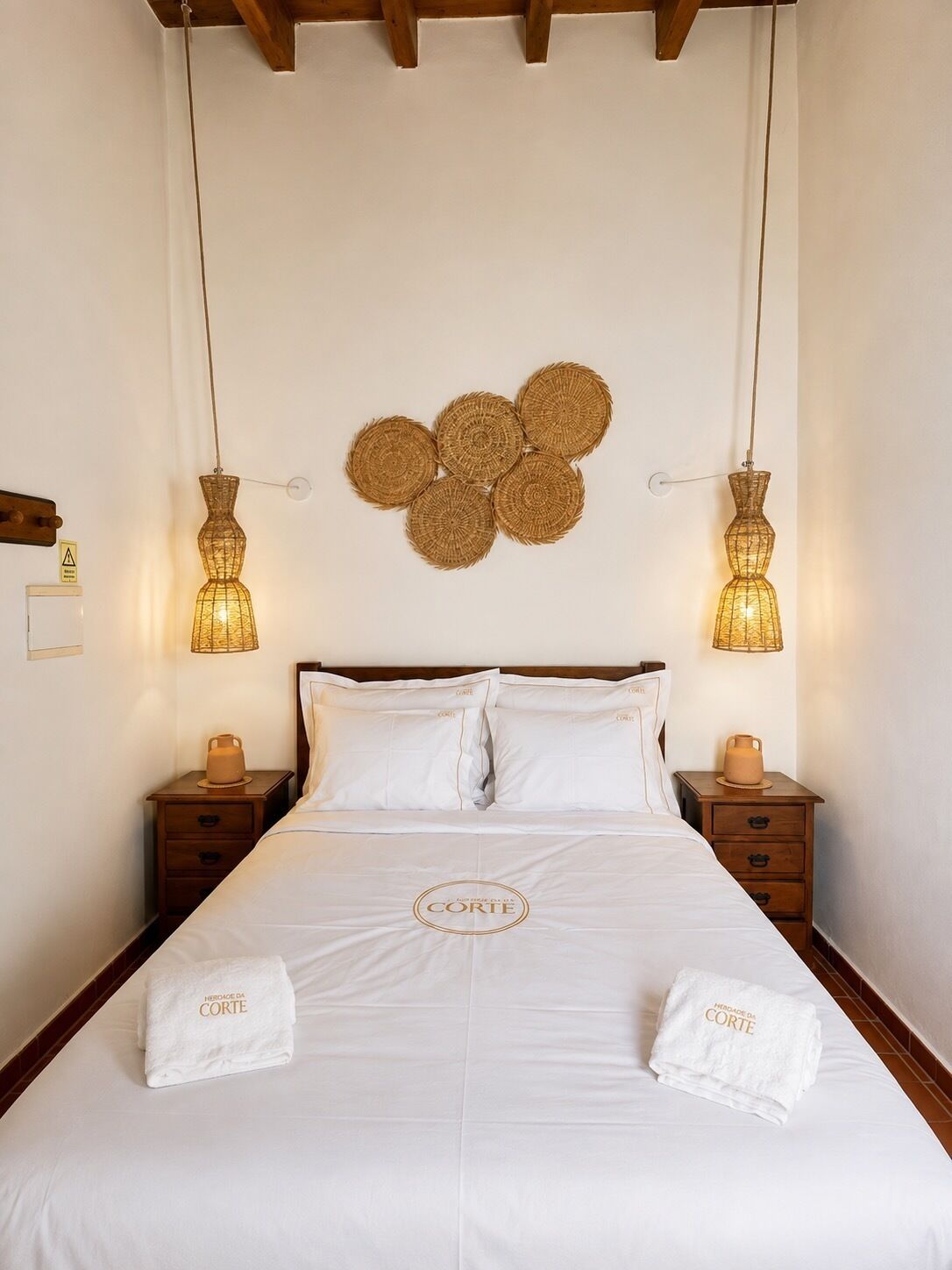 Une chambre d’hôtel avec un grand lit, deux tables de chevet, un luminaire fixé au mur et un élément décoratif mural.