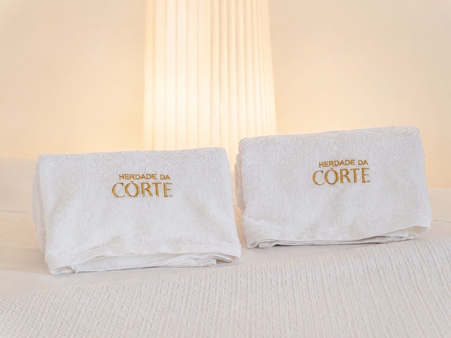 Dos toallas dobladas con texto en relieve sobre una cama.