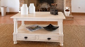 A room with a fireplace, a white table with a magazine, and a potted plant.