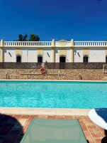 Uma piscina com uma parede de pedra e um edifício ao fundo.
