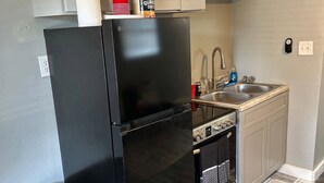 Una cocina compacta con un refrigerador negro, un lavamanos y una estufa.