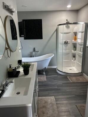 Ein modernes Badezimmer mit einer freistehenden Badewanne, einer begehbaren Dusche und einem großen Spiegel.