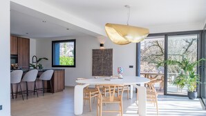 Una cuina moderna amb una zona de bar, taula de menjador amb caires i una finestra gran que proporciona llum natural.