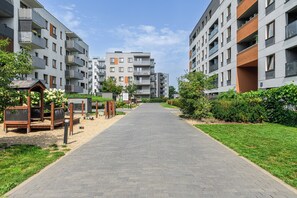 A residential building with multiple balconies, a paved walkway, and greenery. - Lumina 2BR Apart with Parking & Balcony (Warszawa)