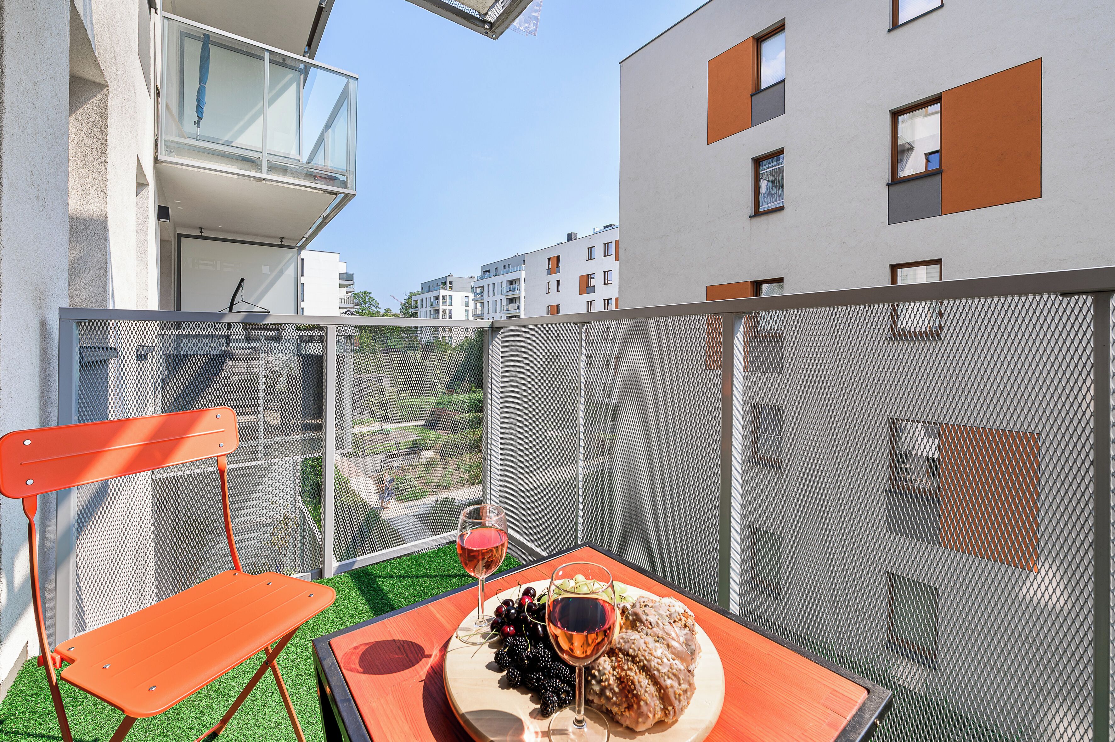 A balcony with a table set for two, a chair, and a view of the cityscape.