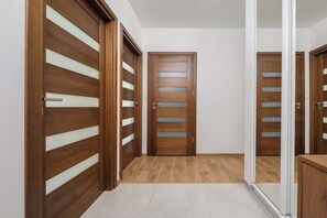 Ein Flur mit Holztüren, die horizontale Lamellen aufweisen, und einer zentralen Tür im gleichen Design.
