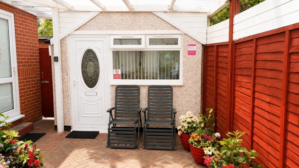 A covered patio area with two black chairs, a white door, and potted plants. - Suite in LS7, Great For Contractors (West Yorkshire)