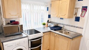 A compact kitchen with a washing machine, a stove, and a sink. - Suite in LS7, Great For Contractors (West Yorkshire)