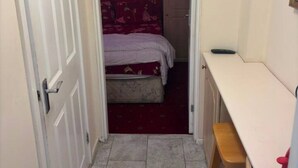 A narrow hallway leading to a bedroom with a bed and a desk. - Suite in LS7, Great For Contractors (West Yorkshire)