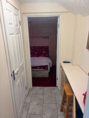 A narrow hallway leading to a bedroom with a bed and a desk. - Suite in LS7, Great For Contractors (West Yorkshire)