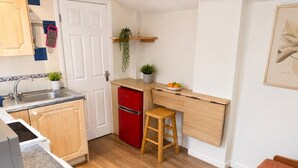 A compact kitchen with a red refrigerator, wooden cabinets, a countertop, and a stool. - Suite in LS7, Great For Contractors (West Yorkshire)