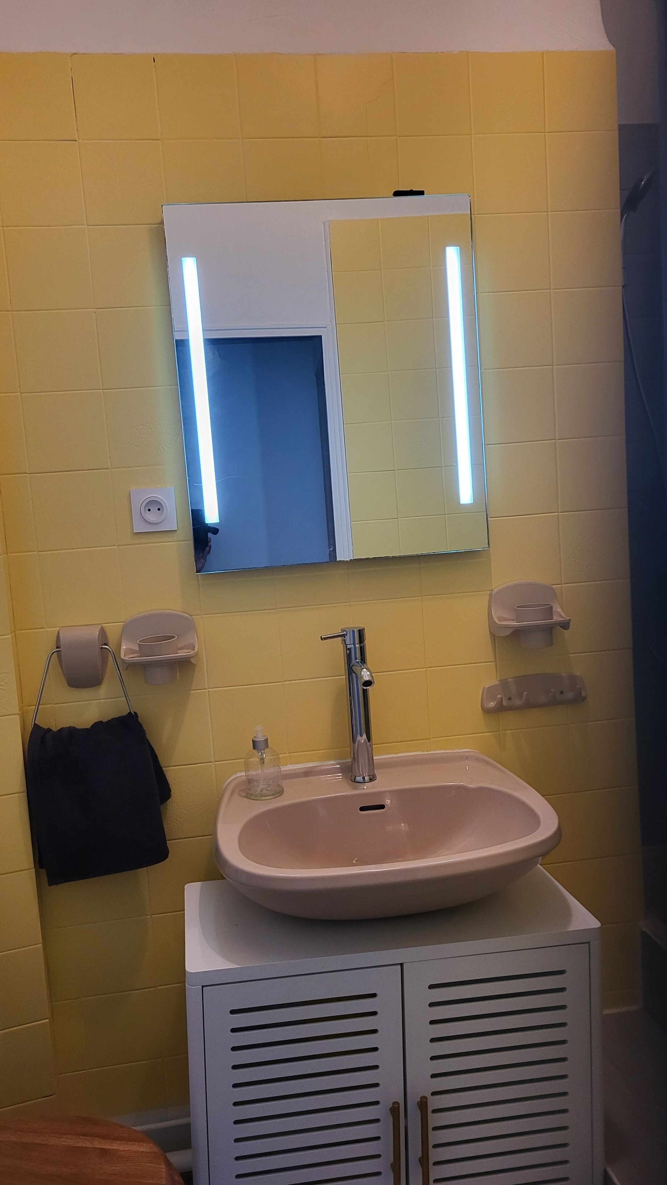 A bathroom with a sink, mirror, and towel rack.