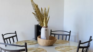 Ein Esstisch mit weißer Tischplatte, umgeben von schwarzen Stühlen, und eine dekorative Vase mit goldenen Blättern.