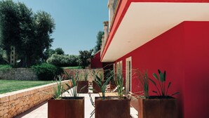 Un edificio rojo con pared de piedra y plantas en macetas al frente.