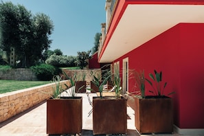 A red building with a stone wall and potted plants in front. - Appartamento Wood - Tenuta Fascianello (Puglia)