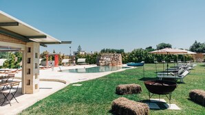 Un patio trasero con piscina, mobiliario exterior y zona de barbacoa.