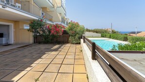 Un edificio residenziale con piscina, patio piastrellato e vista mare.