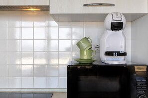 A kitchen with a microwave, a coffee maker, and a green mug on the counter. - Deluxe Apartment with Pool, Sea View, Shared Pool, and Air Conditioning (Paduledda)