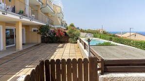 Un edificio residenziale con balconi, una piscina e vista libera sul mare.