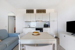 Un espacio habitable compacto con kitchenette, comedor y zona de estar.