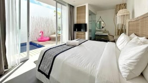 A hotel room with a large bed, a television, a desk, and a view of a swimming pool with a pink flamingo decoration. - Villa Lavana Uluwatu (Badung)