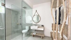A modern bathroom with a glass shower enclosure, a toilet, a sink with a mirror, and a wooden bench. - Villa Lavana Uluwatu (Badung)
