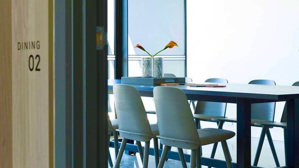 A modern dining area with a table and chairs, a vase with flowers, and a window with a view. - CASA DELUXE #5 - Pool Gym Sauna Spa City Views Parking (South Yarra)